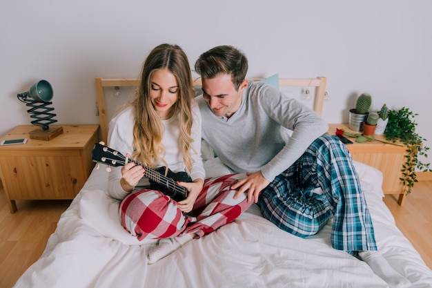 Free photo man teaching woman playing ukulele