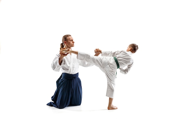 Man and teen boy fighting at Aikido training in martial arts school. Healthy lifestyle and sports concept. Fightrers in white kimono on white background. Karate men with concentrated faces in uniform.