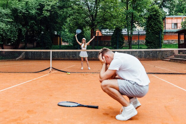 Man, tennis teacher, showing woman how to play the racket sport outdoors.