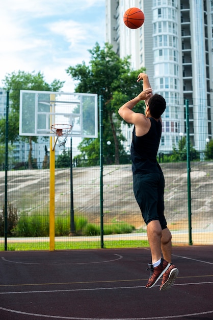 バスケットボールのフープにボールを投げる男