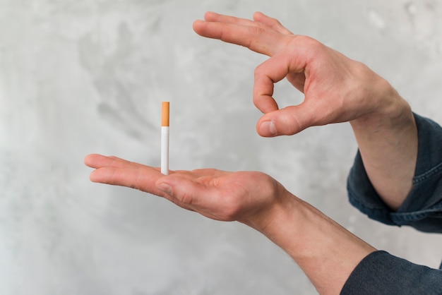 Free photo man throwing cigarette through finger against wall