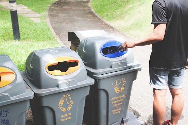 Free photo man throwing plastic bottle in recycle trash can