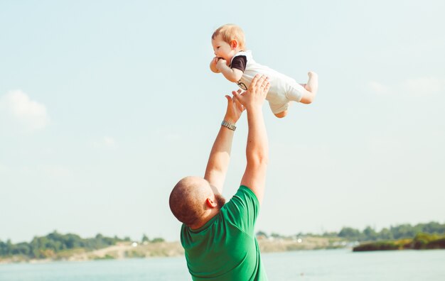 "Man throwing up baby on landscape"