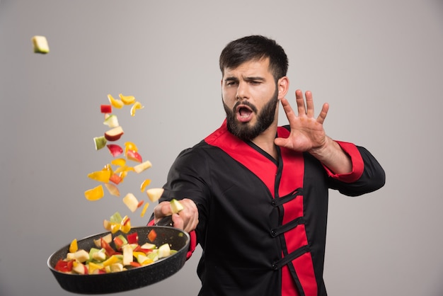 Free photo man throwing vegetables from pan .