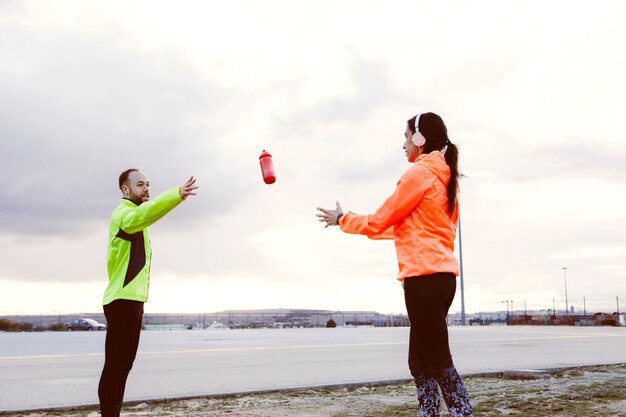 Man throwing water bottle towards woman