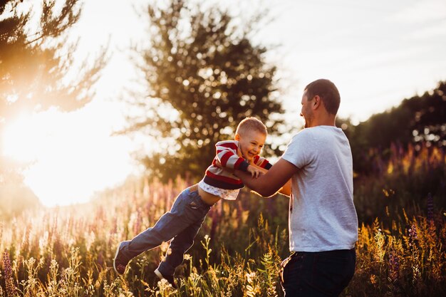 Человек бросает своего сына на поле в свете вечернего солнца