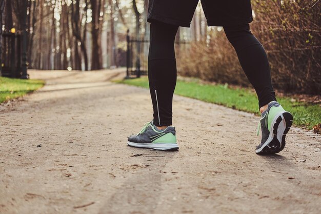 Man in tights and shorts is running on the path at the park.