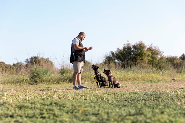 Мужчина тренирует двух своих собак на улице