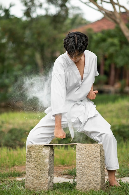 Мужчина тренируется в тхэквондо на открытом воздухе на природе
