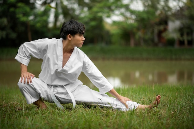 Foto gratuita uomo che si allena nel taekwondo all'aperto in natura