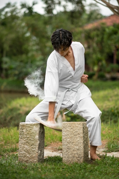 Foto gratuita uomo che si allena nel taekwondo all'aperto in natura