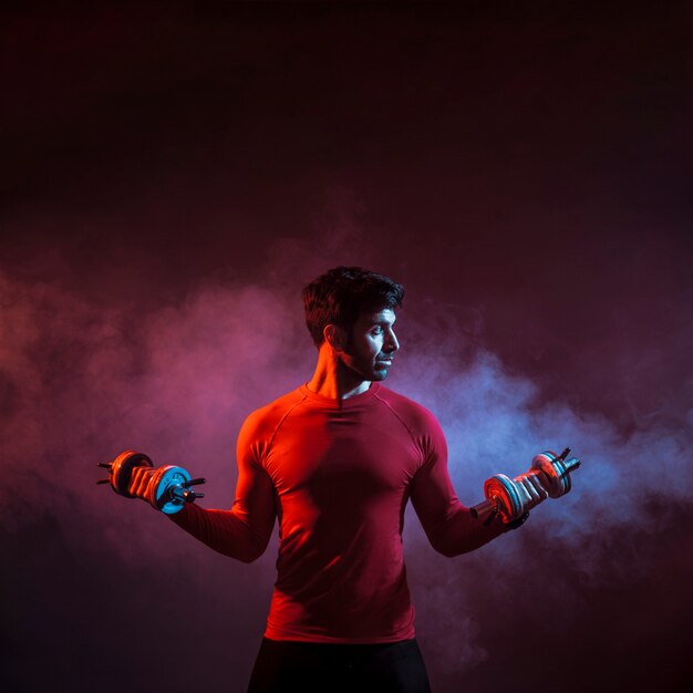 Man training with dumbbells in smoke