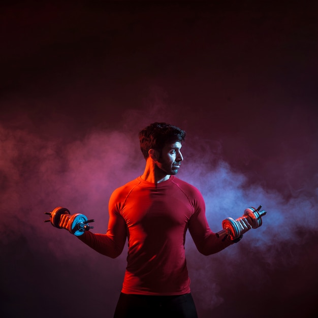 Man training with dumbbells in smoke