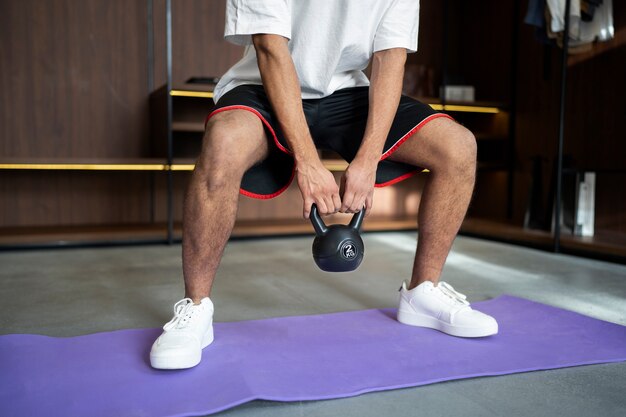 Man training with kettlebell on mat