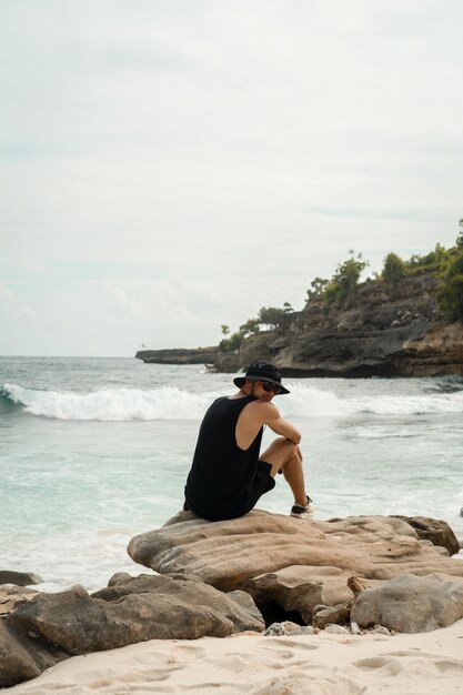 Man traveler on a rock by the ocean.