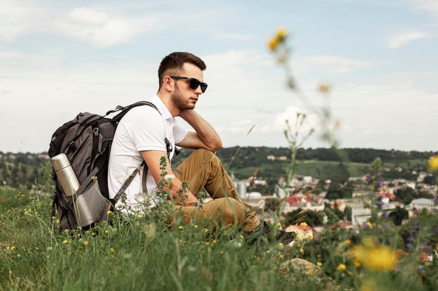 Man traveling alone resting on green field