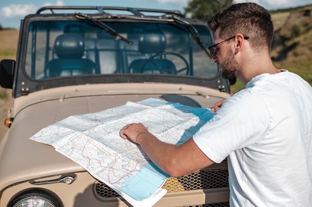 Free photo man traveling by car and checking map