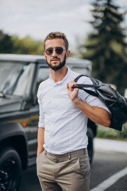 Man travelling with bag and standing by the car