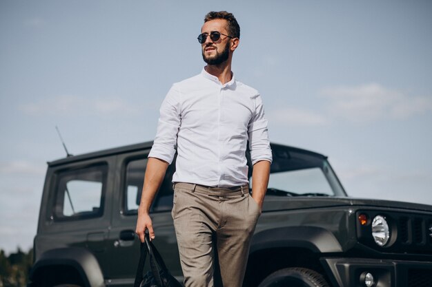 Man travelling with bag and standing by the car