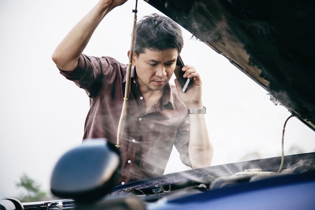 Free photo man try to fix a car engine problem on a local road