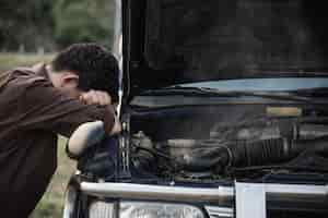 Free photo man try to fix a car engine problem on a local road