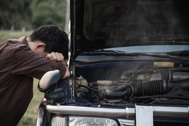 Man try to fix a car engine problem on a local road 