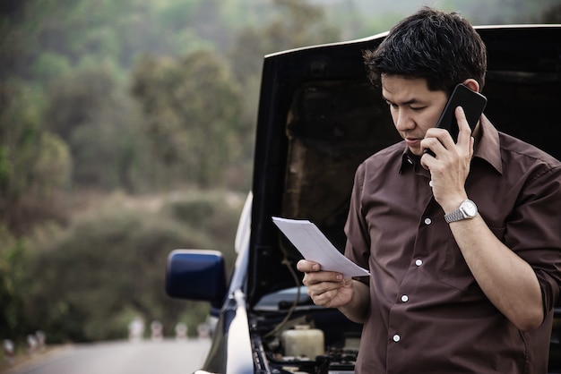 Free photo man try to fix a car engine problem on a local road