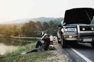 Free photo man try to fix a car engine problem on a local road