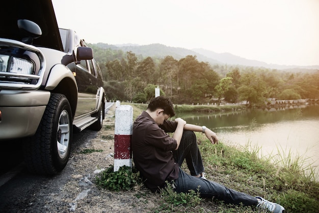 Man try to fix a car engine problem on a local road 