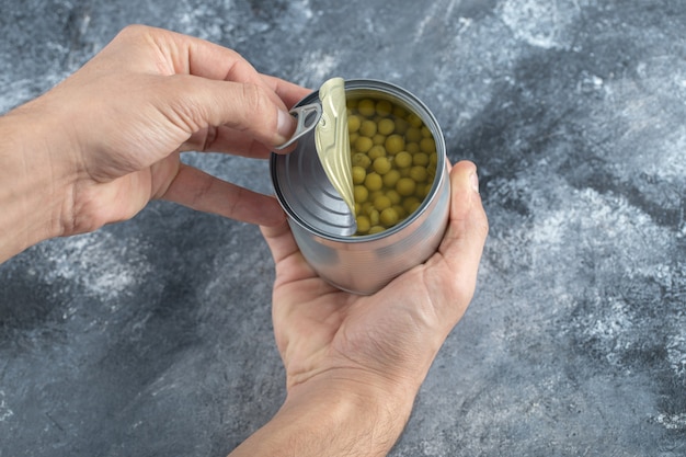 Man trying to open tin. green peas.