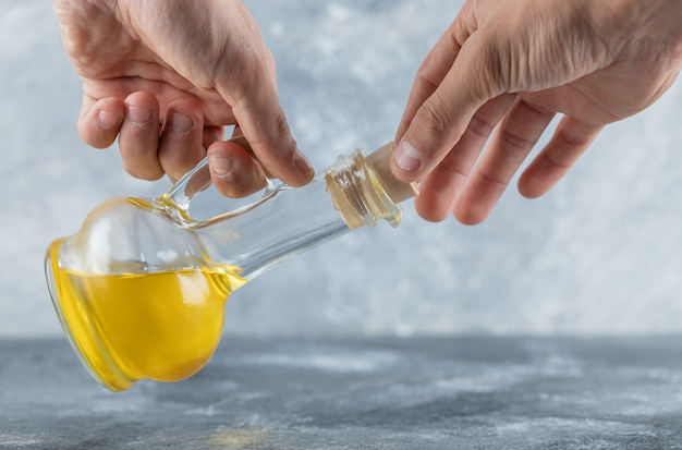 Uomo che cerca di aprire una bottiglia di olio. foto di alta qualità