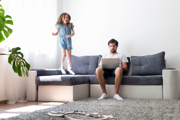 Foto gratuita uomo che cerca di lavorare su un laptop da casa mentre i suoi figli corrono in giro