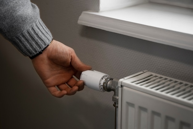 Мужчина выключает радиатор во время энергетического кризиса