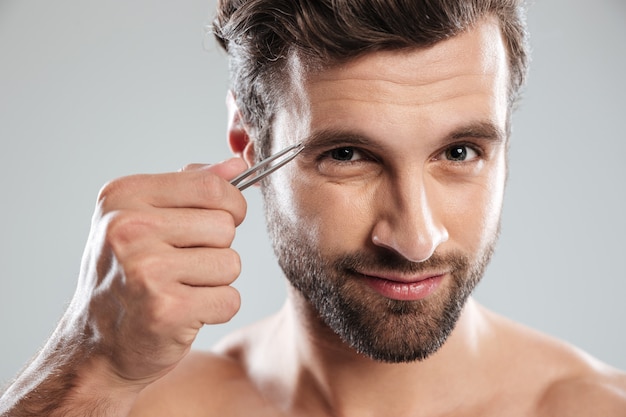 Man tweezing his eyebrows isolated