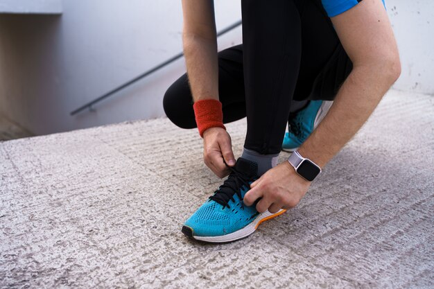 Man tying his sport shoes on concrete background