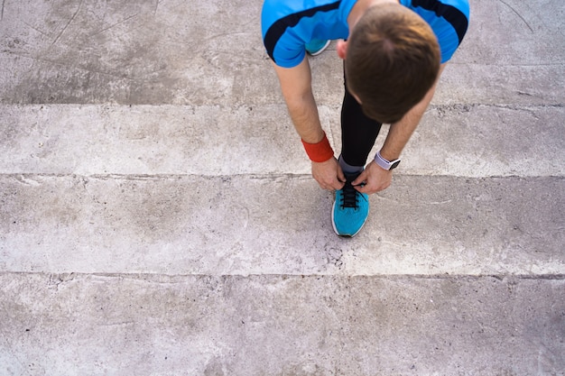 Человек, связывая его спортивную обувь на бетонном фоне