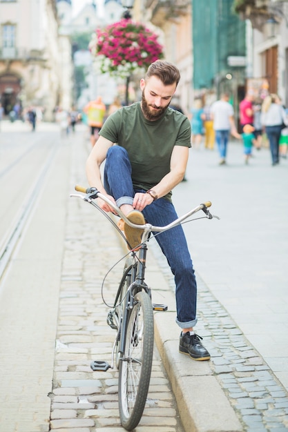 自転車に乗る前に靴を結ぶ男