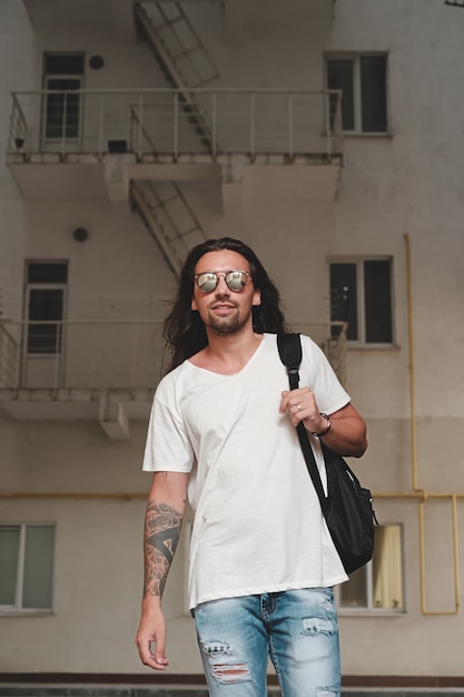 Man on urban scene with backpack and sunglasses