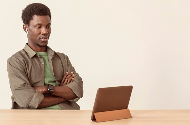 Человек, использующий воздушные капсулы и смотрящий на цифровой планшет
