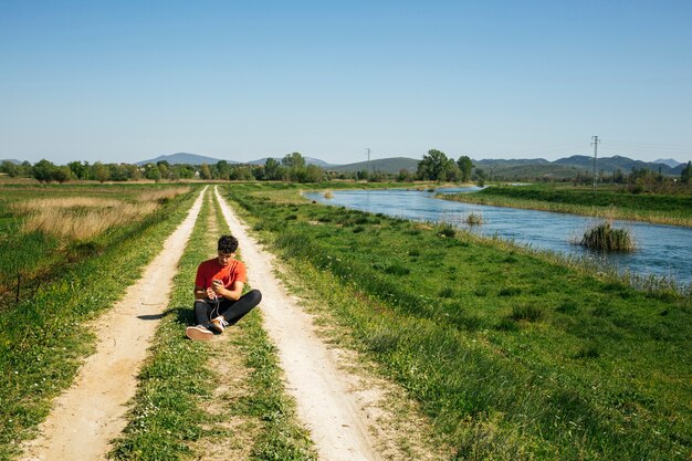 Man using cellphone siting on diminishing pathway