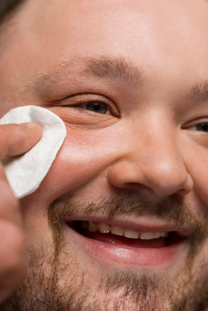 man using cotton pad on his face for skincare