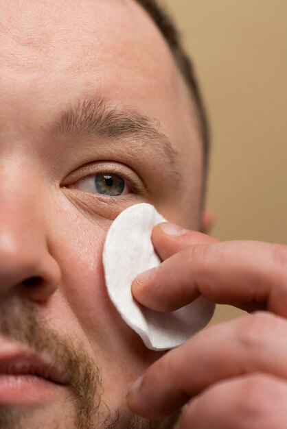 Man using cotton pad on his face for skincare