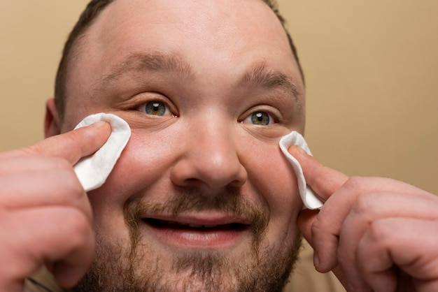 Бесплатное фото Мужчина использует ватные диски на лице для ухода за кожей