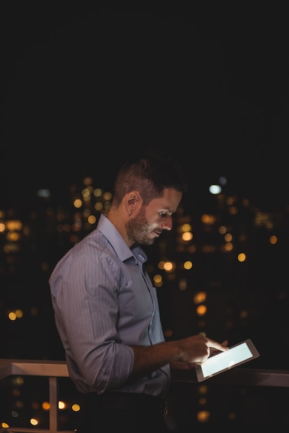 Человек с помощью цифрового планшета на балконе