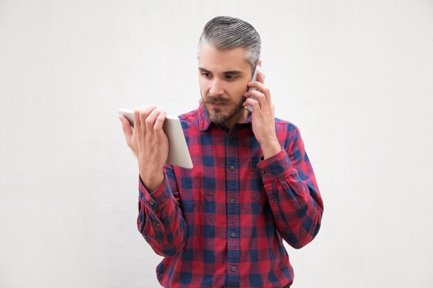 Man using digital tablet and talking by smartphone