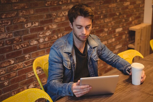 Man using digital tablet while having coffee