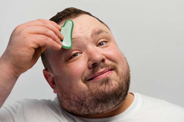 Man using gua sha on his face for skincare