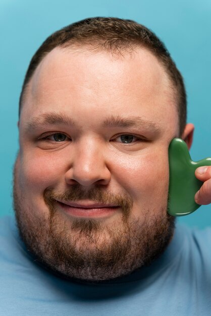 Man using gua sha on his face for skincare