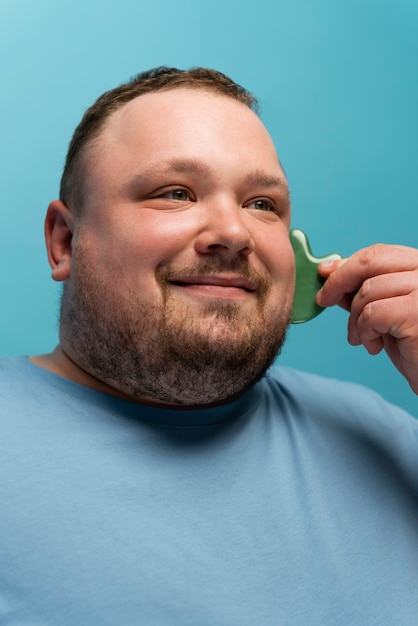 Man using gua sha on his face for skincare