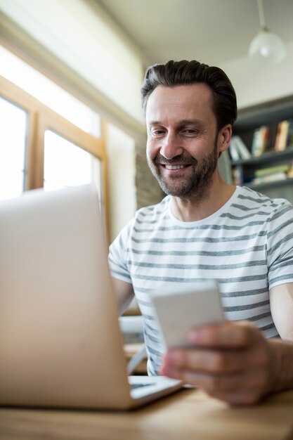 コーヒーショップで彼のノートパソコンと携帯電話を使用して男